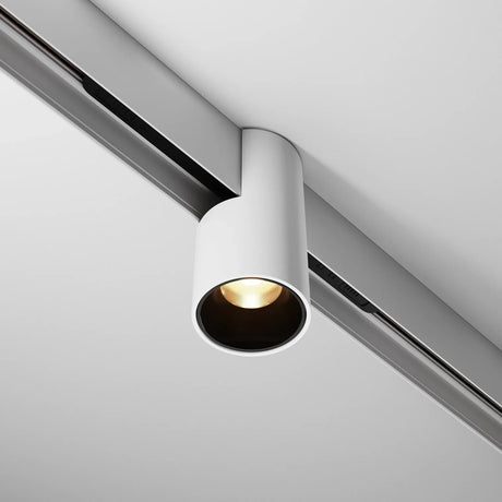 A modern, cylindrical white ceiling light fixture attached to a track system, emitting a focused beam of light downward.
