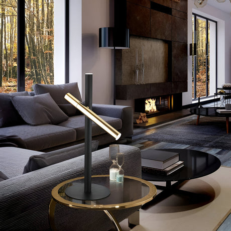 Modern living room with a sleek lamp on a glass side table, grey sofa, and round black coffee table. Large windows showcase a forest view, and a fireplace adds warmth to the stylish, minimalist decor.