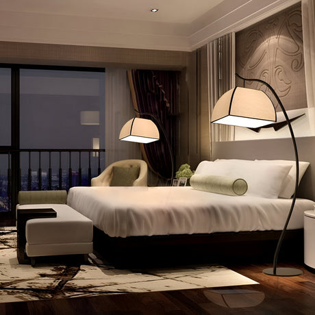 A modern bedroom with a large bed, decorative lamp, armchair, and floor rug. Floor-to-ceiling windows reveal a night cityscape. The walls are adorned with patterned art.