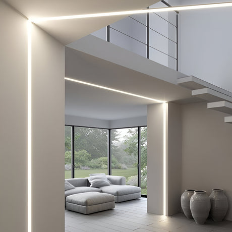 Modern living room with large windows, minimalistic gray sofa, and potted vases on the floor. Soft natural light highlights the space, while sleek linear lighting defines the ceiling and walls.