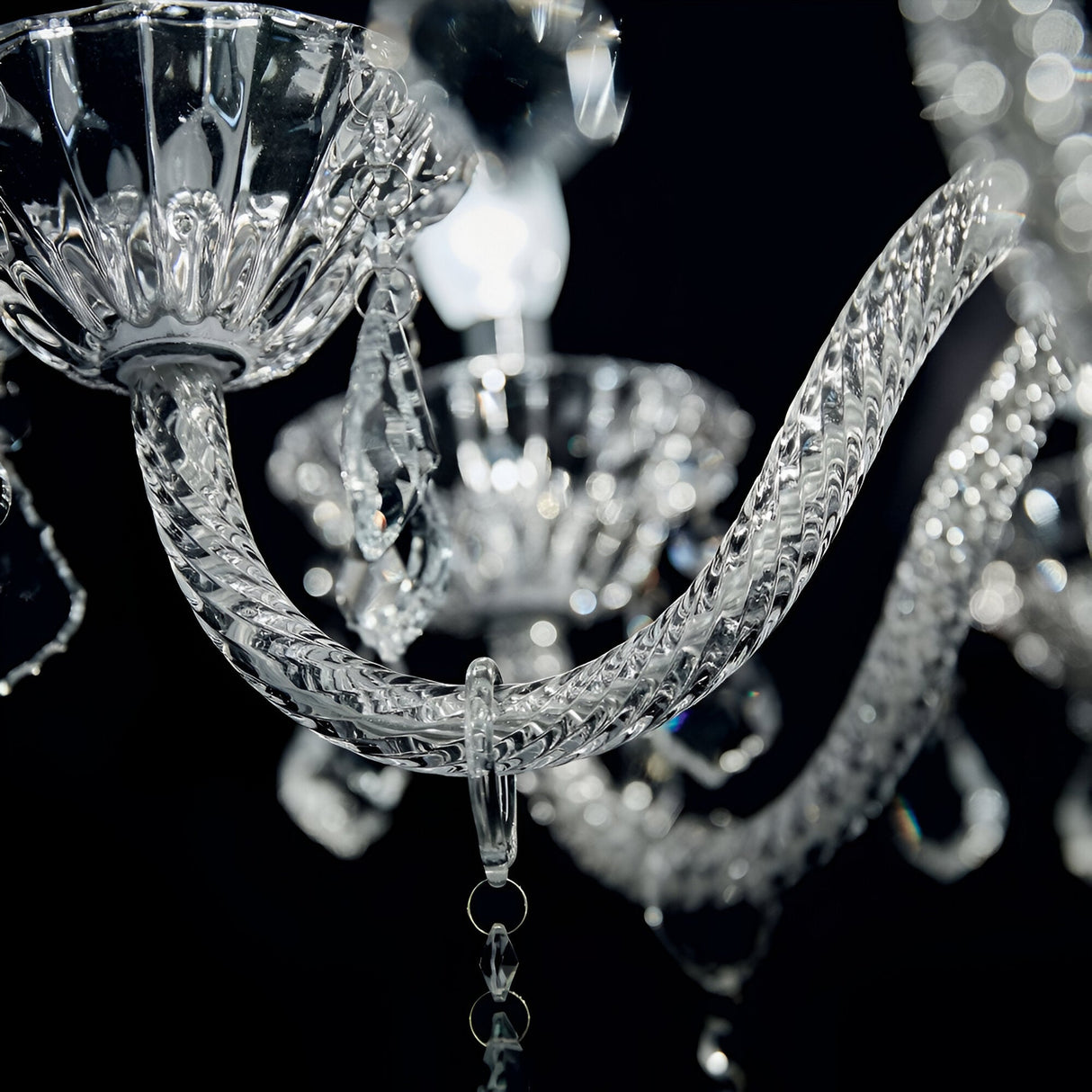 Close-up of the Nimble Crystal 8 Light Chandelier - Chrome against a dark background. The image highlights the intricately twisted hand-blown glass arms and dangling crystal pendants, reflecting light and creating a sparkling effect.