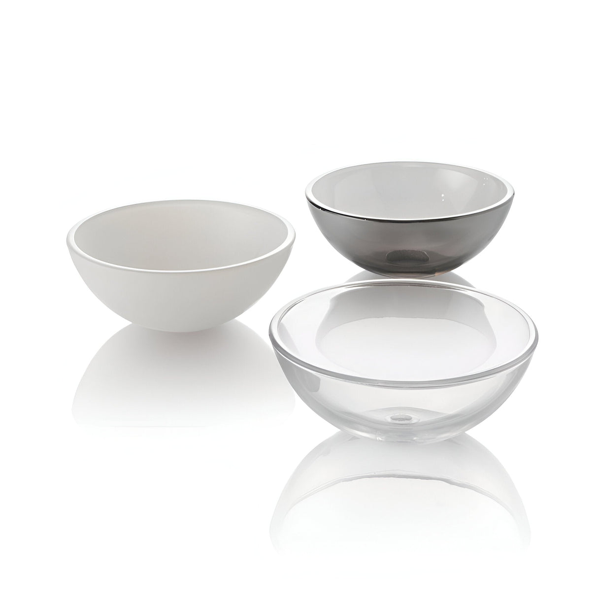 Arranged like the Casio Glass 8 Light Chandelier in chrome, three ceramic bowls sit on a white surface featuring an opaque white bowl, a translucent grey one, and a clear glass bowl.