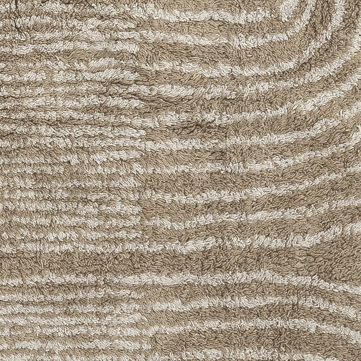 Zeynep Cotton Rug 215x150cm in brown, close-up of tufted cotton pile with curved wave-like lines in a lighter tone against a brown background.