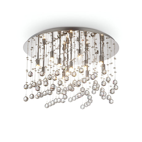 The Solisera 12 Light Crystal Semi Flush Chandelier - Chrome features a modern design with a circular base. It showcases numerous glass crystal strings hanging at varying lengths, creating a shimmering raindrop effect. The chrome finish on the metallic base enhances its elegant appearance.