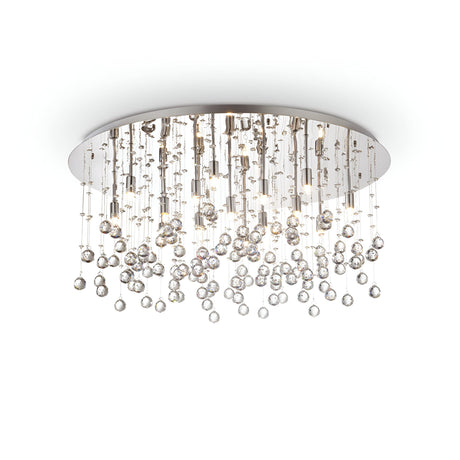 The Solisera 15 Light Crystal Semi Flush Chandelier in chrome boasts a stunning design, featuring a circular base adorned with cascading spheres and rods. It illuminates brilliantly, casting dazzling reflections that beautifully light up the space below.