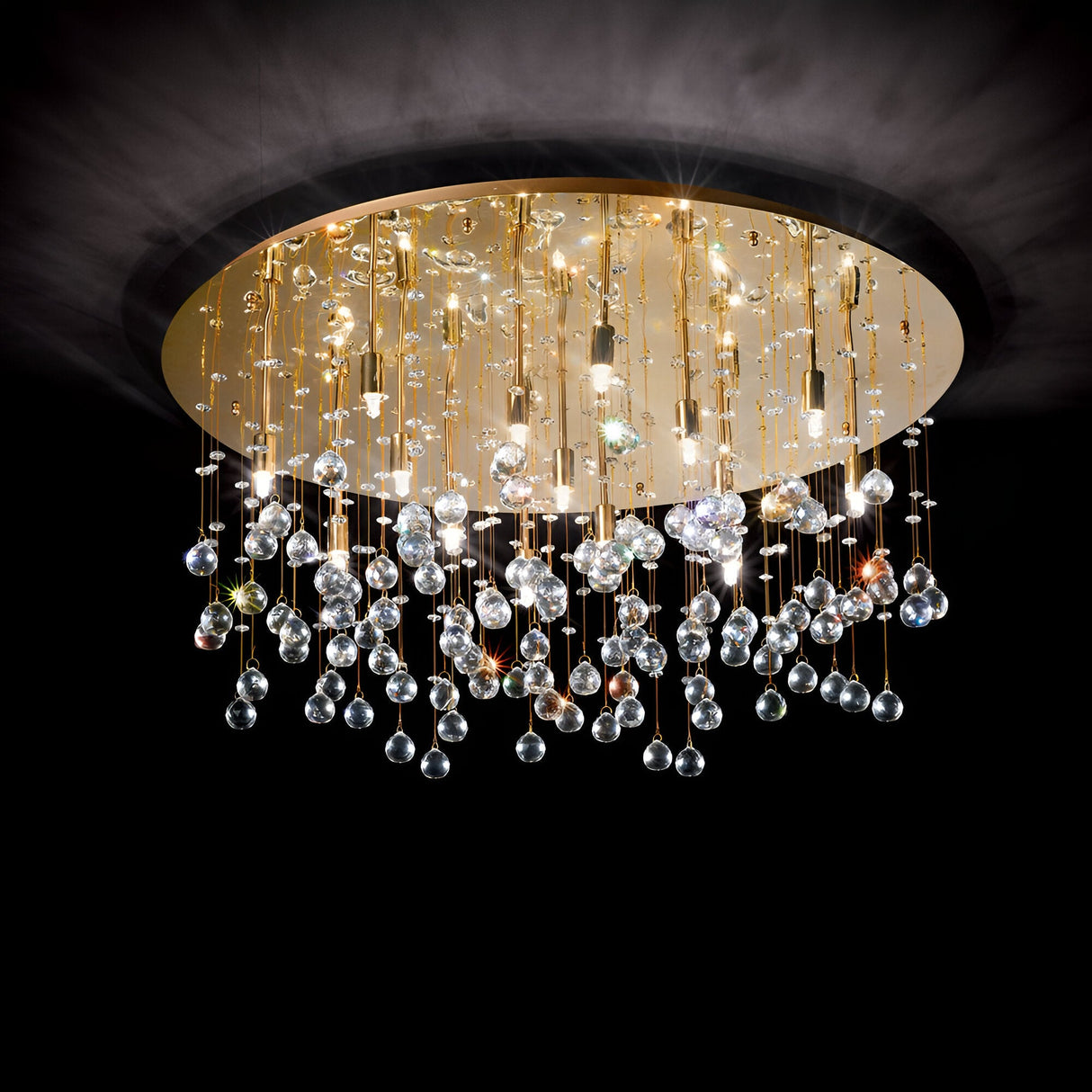 The Solisera 15 Light Crystal Semi Flush Chandelier in gold boasts a circular base and numerous crystal pendants with small lights, casting a sparkling effect against a dark background.
