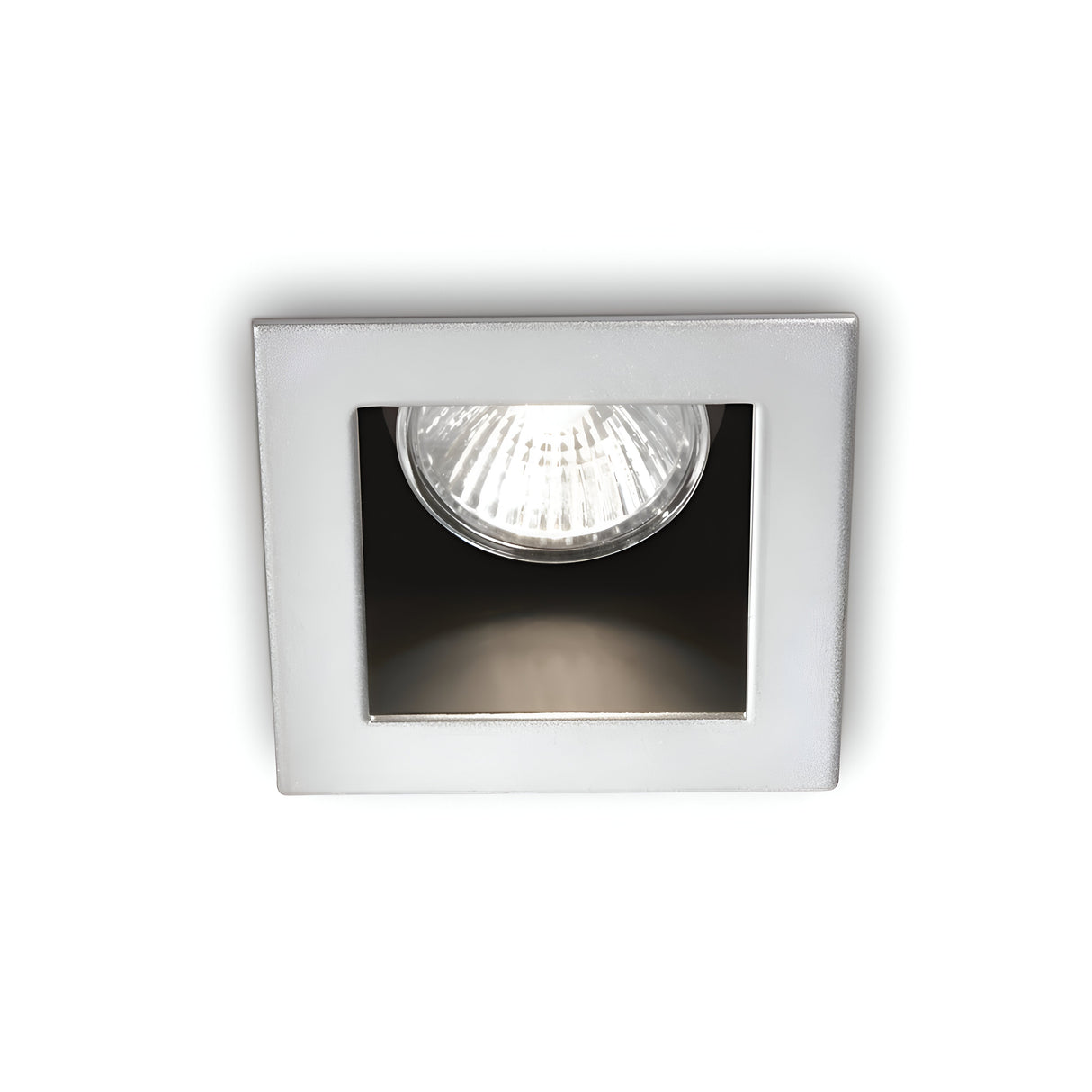 The Shimmer Recessed Downlight - Grey features a square design with a visible bulb that is partially enclosed within its modern fixture, casting a bright white light against the plain white background.