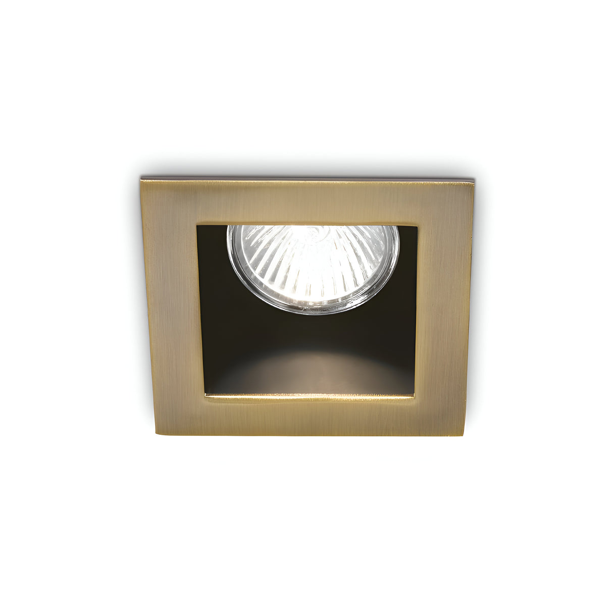 The Shimmer Recessed Downlight - Brass features a square design with a brushed metal frame and a visible circular bulb at its center, perfect for illuminating modern interiors. This brass downlight emits a warm glow against a pristine white backdrop, effortlessly merging elegance with functionality.