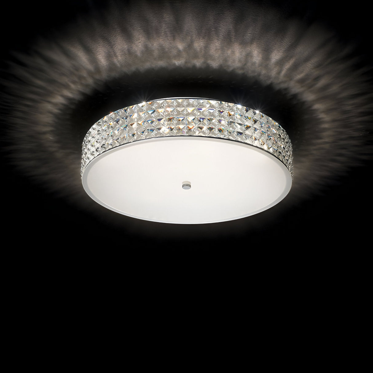 The Nebula 9 Light Crystal Ceiling Light - Chrome elegantly enhances modern interiors with its round fixture and decorative crystal-like edge, emitting a soft, radiant glow against a black background. Its design creates a mesmerizing patterned light effect on the ceiling.