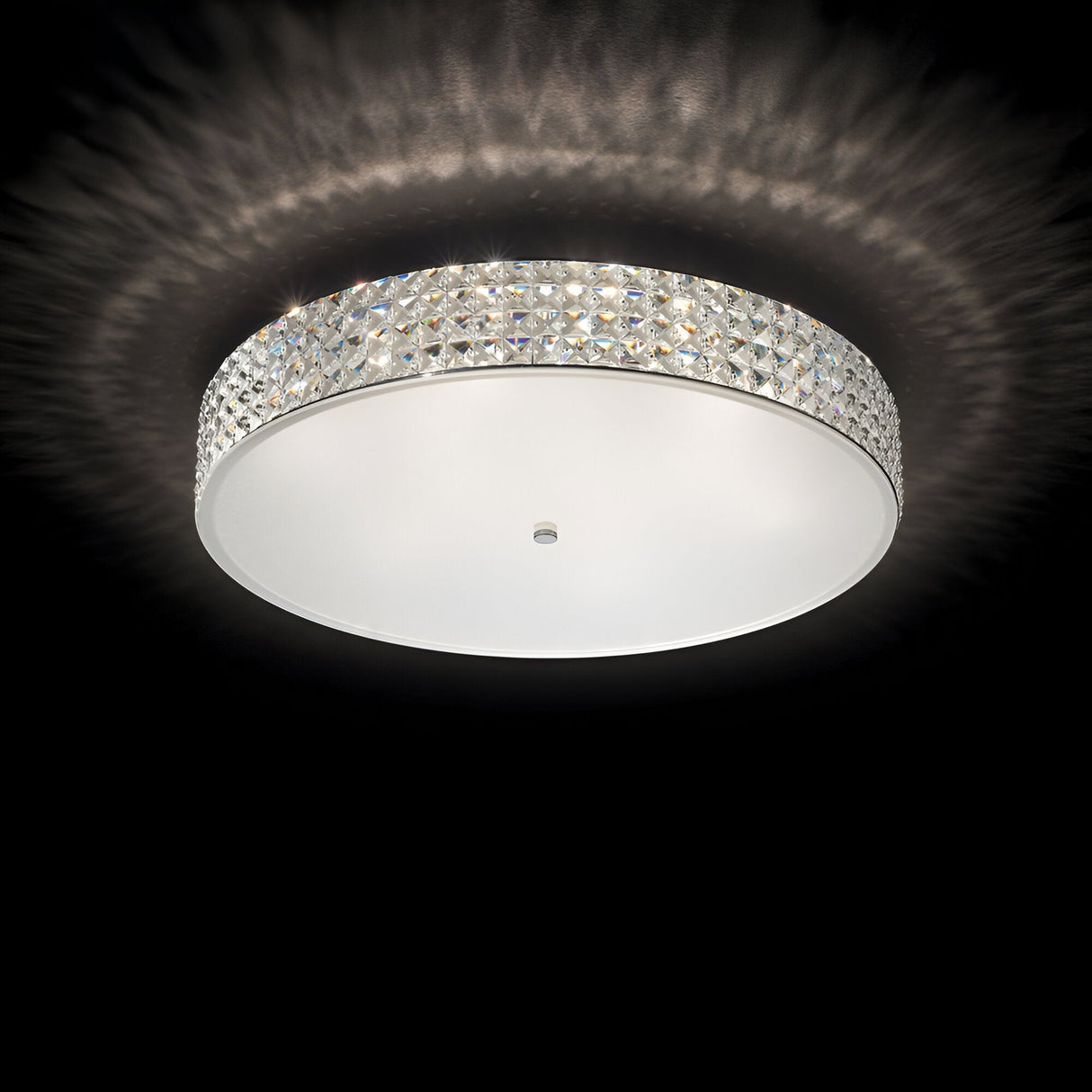 The Nebula 12 Light Crystal Ceiling Light - Chrome features a diamond-patterned crystal border that casts a soft glow against a dark background, epitomizing modern design lighting.