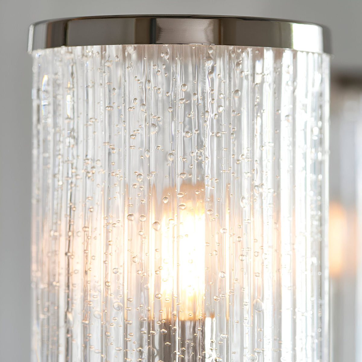 Close-up of Endon Brenfield pendant shade showing clear ribbed cylindrical glass with bubble detail, nickel metal cap, and lit E14 bulb inside.