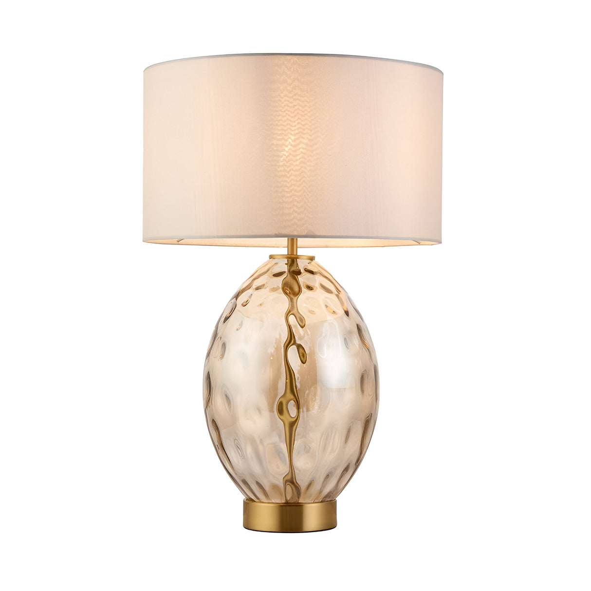 Endon Draycott table lamp with a dimpled amber glass oval base, satin brass fittings and a vintage white fabric drum shade, lit on a white background.