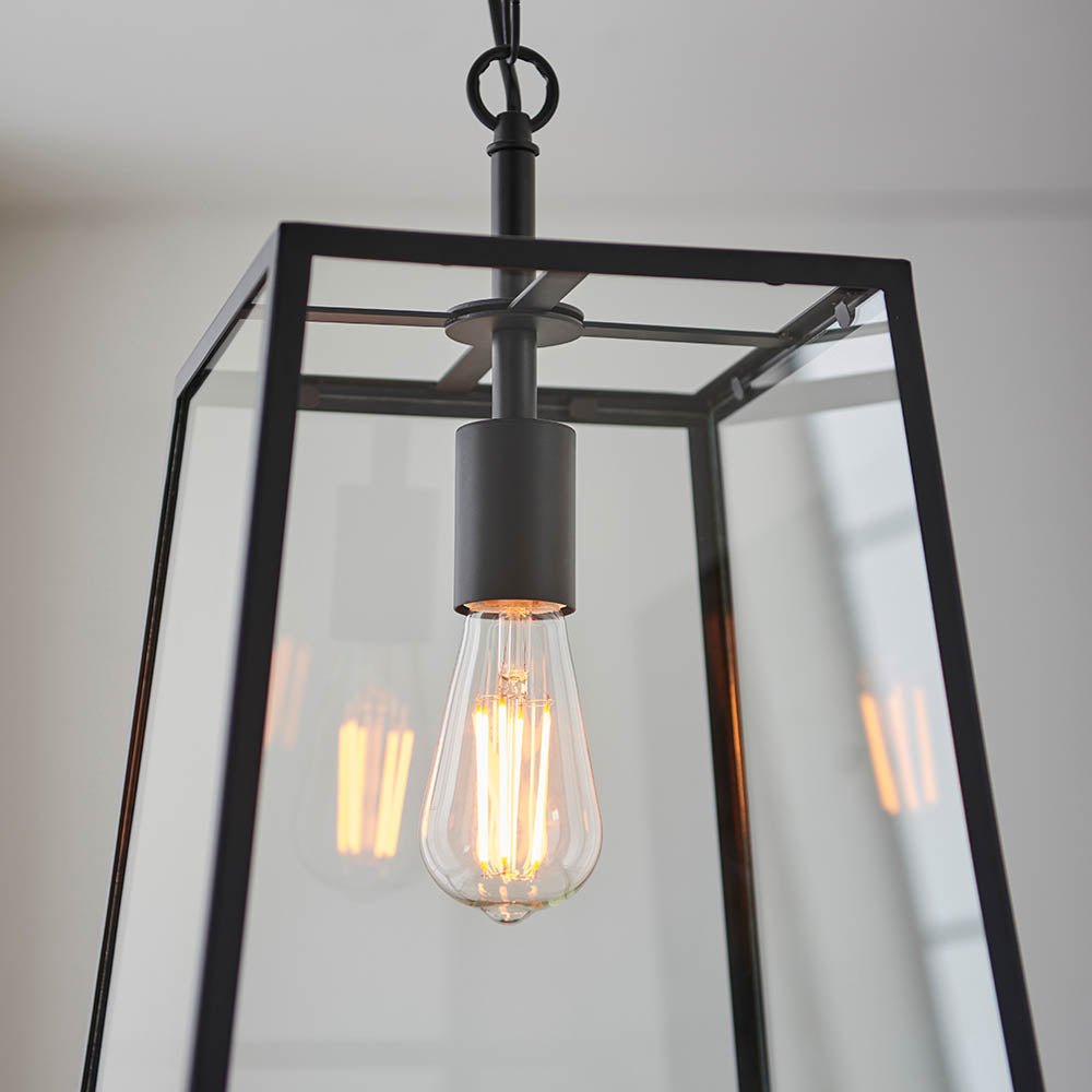 Brenton Lantern Pendant in black, close-up of the box-frame glass shade with an exposed E27 filament bulb hanging from a black rod.