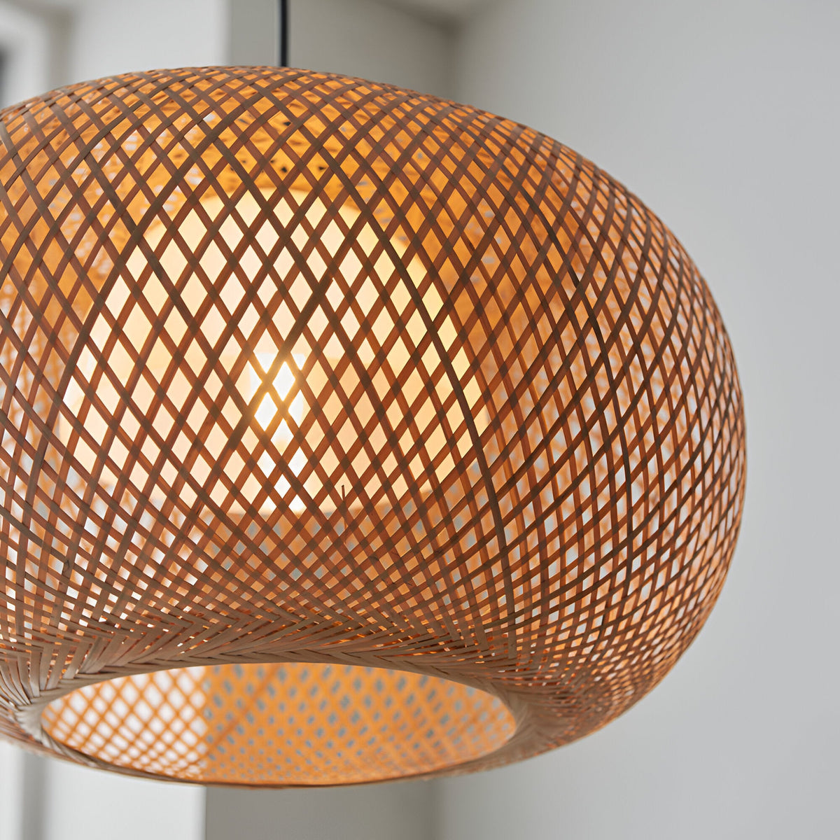 Endon Aldstead globe pendant light with woven natural rattan shade, white inner diffuser and matt black flex, illuminated in a bright interior.