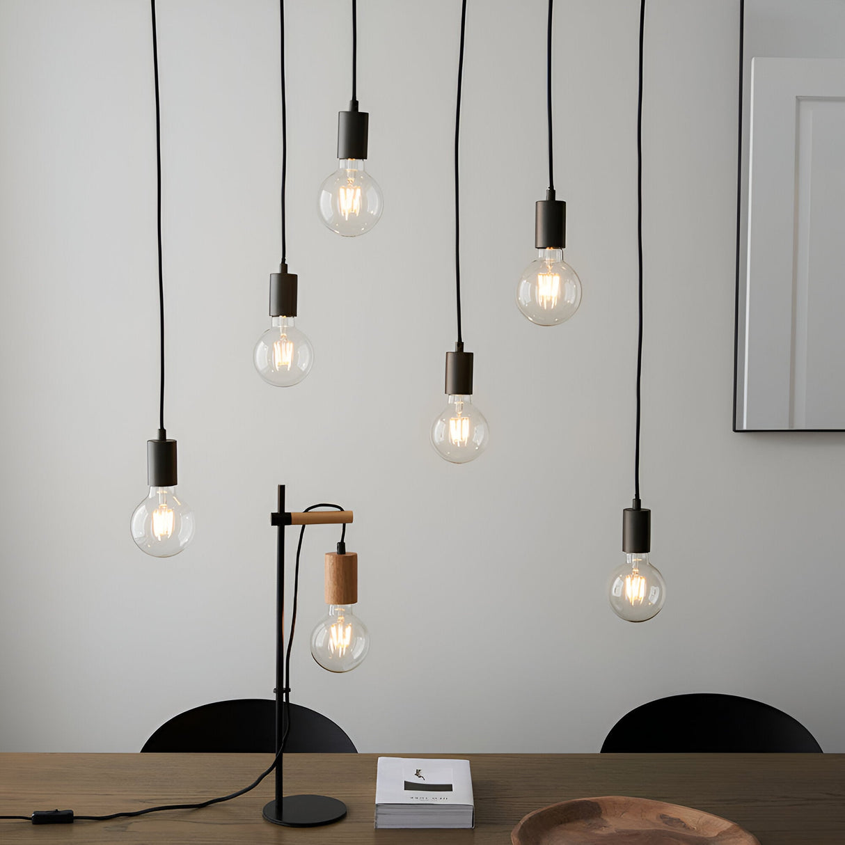 Endon Cliffwell 6 light linear pendant with exposed filament bulbs on black flexes, shown above a dining table with a matching wood and metal desk lamp.