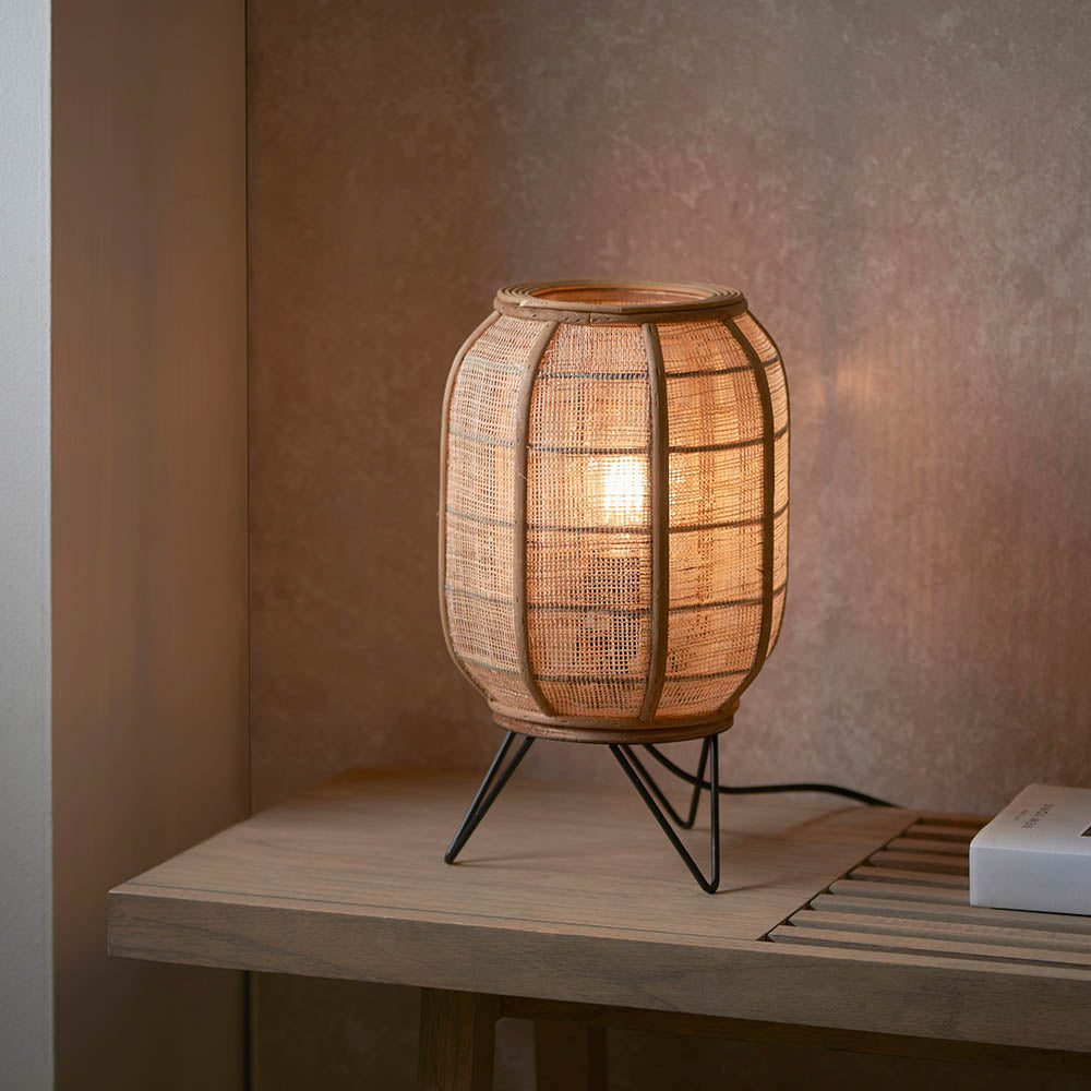 Endon Daneshaw table lamp with a lantern-shaped natural linen and bamboo shade on a matt black wire base, lit on a wooden console.