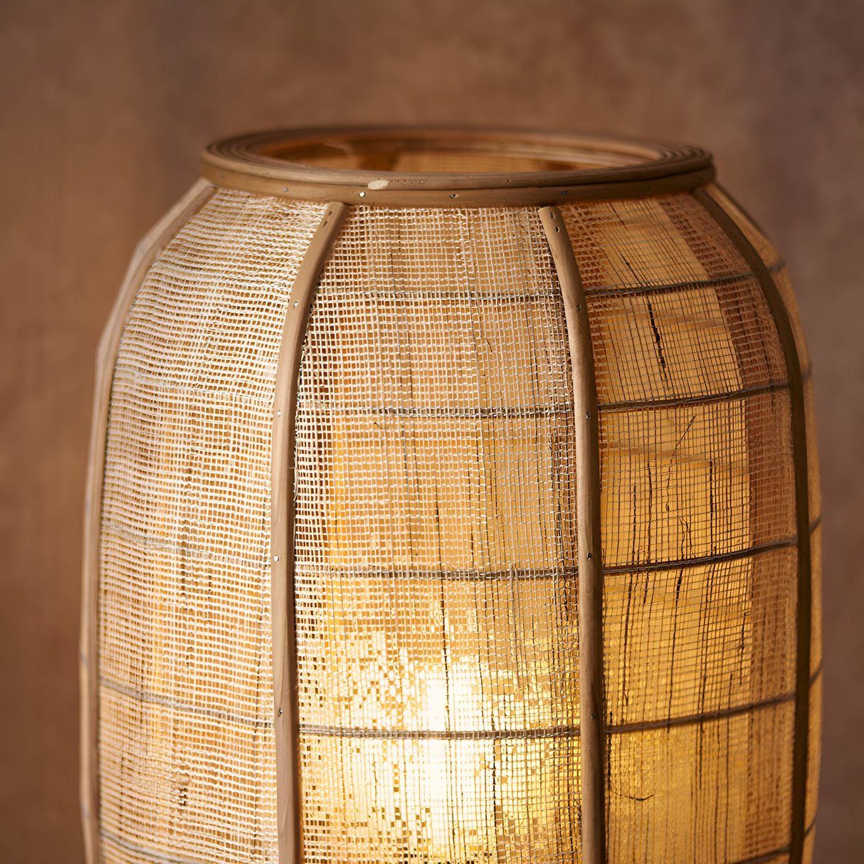 Daneshaw Floor Lamp close-up showing the woven natural linen shade over a bamboo frame with visible ribs, glowing warmly when lit.