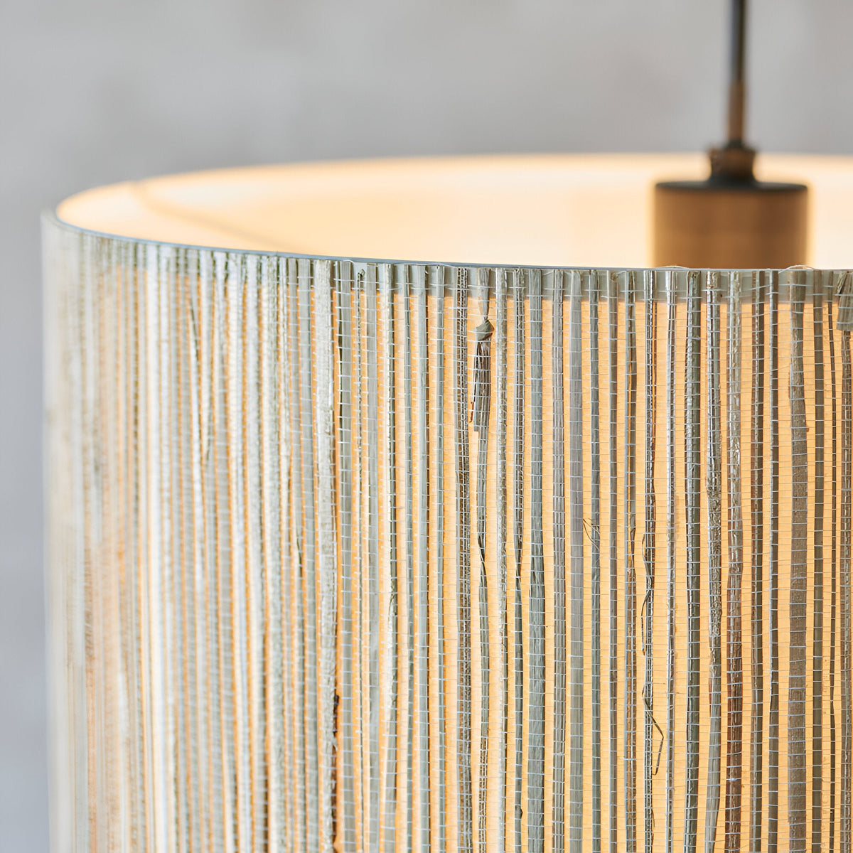 Close-up of the Salcombe Pendant Light's woven natural seagrass drum shade with matt black metal fittings and cable, set against a plain grey background.