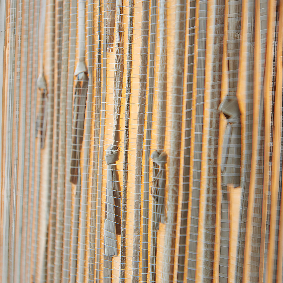 Close-up of the Endon Salcombe pendant's woven natural seagrass shade, showing the vertical grain lit with a warm glow.