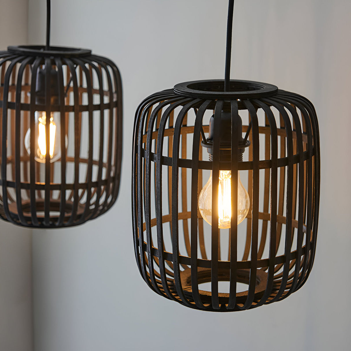 Endon Bracken pendant lights with black bamboo cage shades and warm filament E27 bulbs, shown lit against a pale wall.
