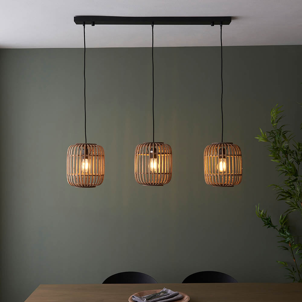Endon Bracken 3 Light Pendant in black and natural, three bamboo cage shades on a linear bar with exposed filament bulbs above a dining table.