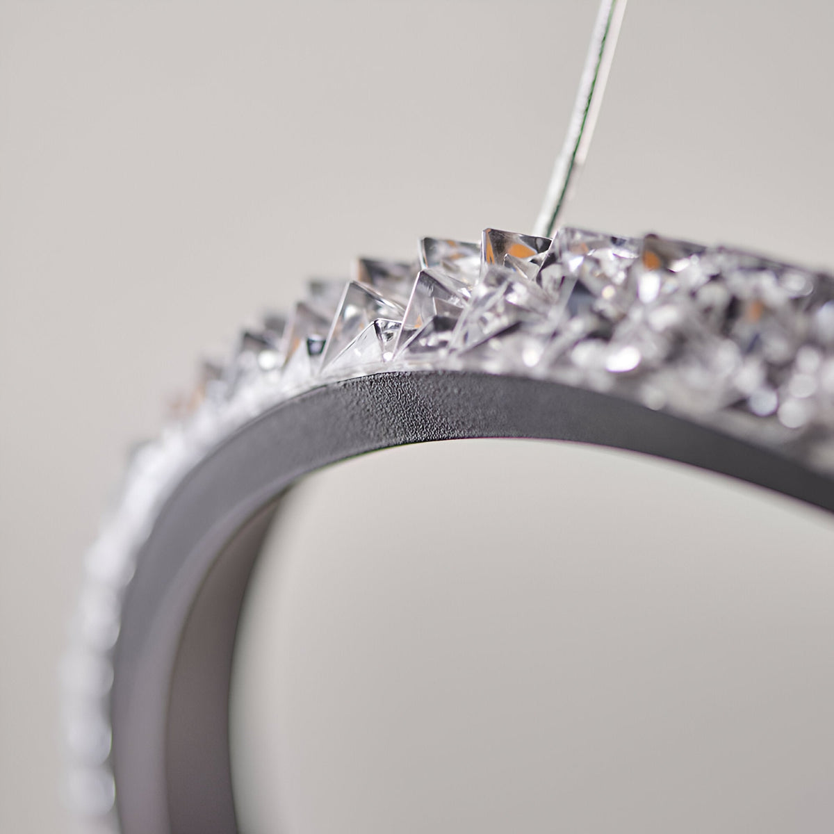 Close-up of the Bramcombe Pendant showing a matt black curved ring edge lined with clear faceted acrylic crystals against a plain light background.