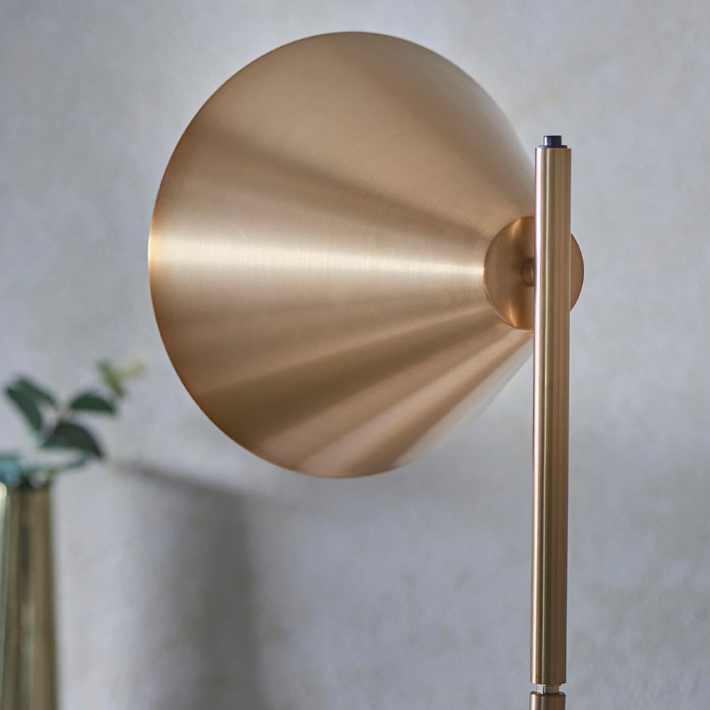 Close-up of the Endon Ashworth floor lamp's brass conical shade and cylindrical stem, shown against a pale neutral background.