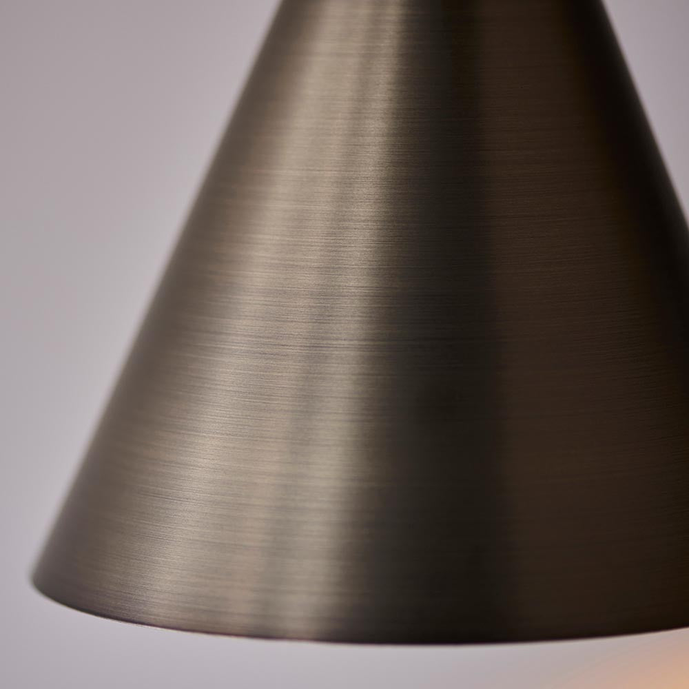 Close-up of the Endon Ashworth wall light's conical shade in brushed antique bronze, showing the finely grained metal finish against a pale background.