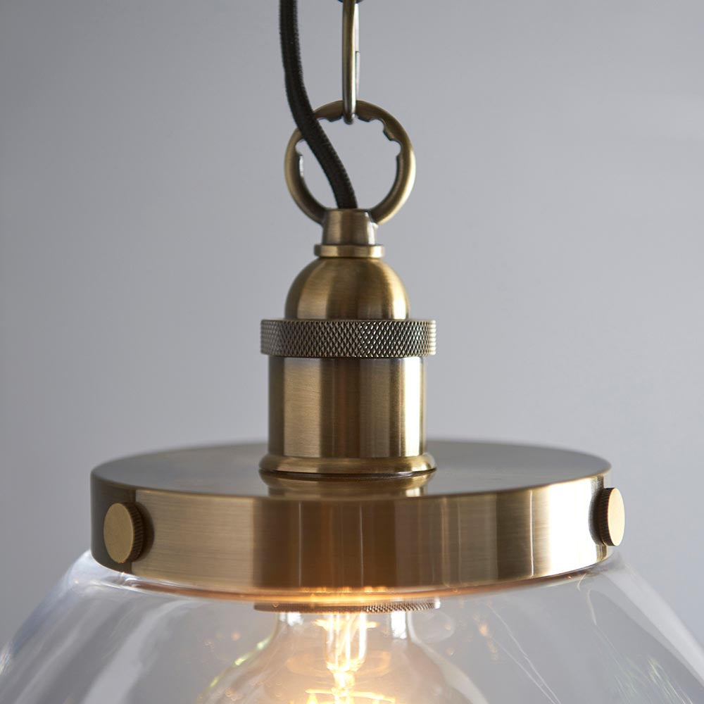Wentworth Pendant in brass with knurled E27 lampholder, clear glass shade, visible filament bulb, hook and chain, on light grey background.