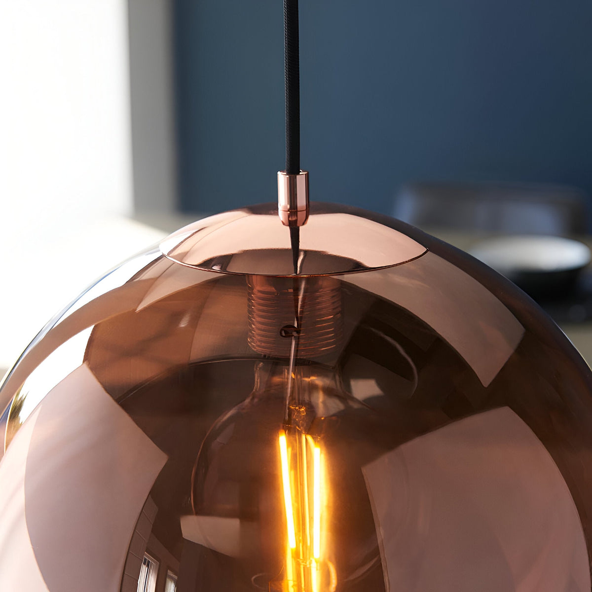 Endon Ashbourne pendant close-up showing the copper mirrored glass globe shade with lit E27 filament bulb inside and black fabric cable.