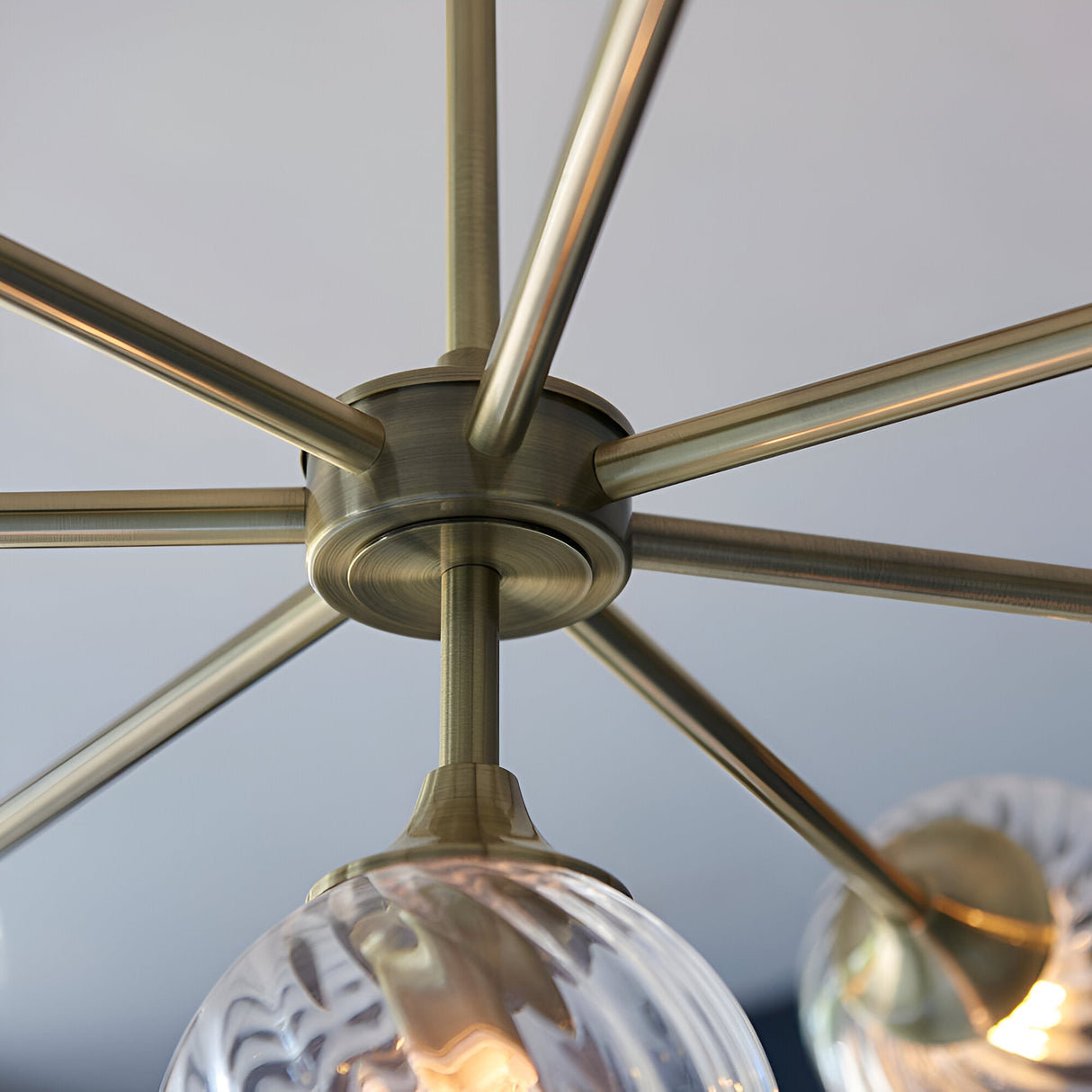 Close-up of Endon Georgiana 8 light pendant showing antique brass spoked frame and a spiral-cut clear glass shade below.