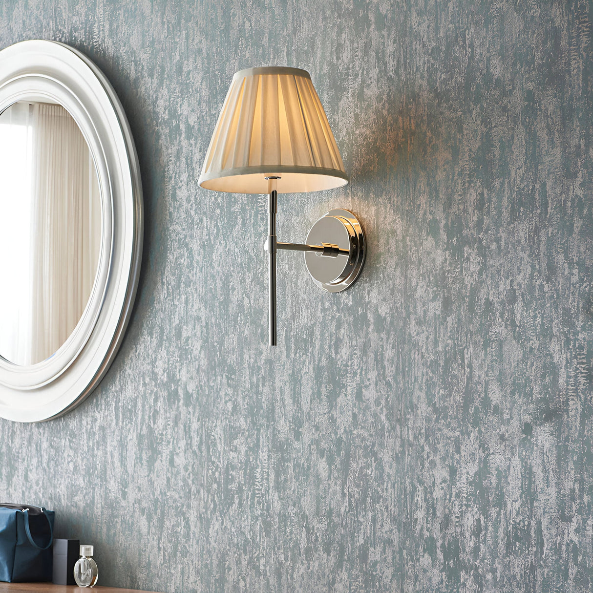 Endon Chartwell wall light with pleated cream cotton shade and nickel bracket, mounted on a textured grey wall beside a round white-framed mirror.