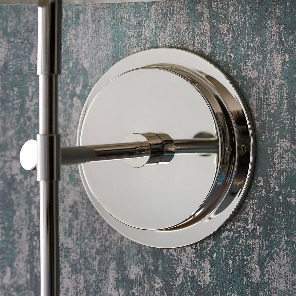 Close-up of the Endon Chartwell wall light's polished nickel circular backplate and bracket mounted on a textured teal wall.