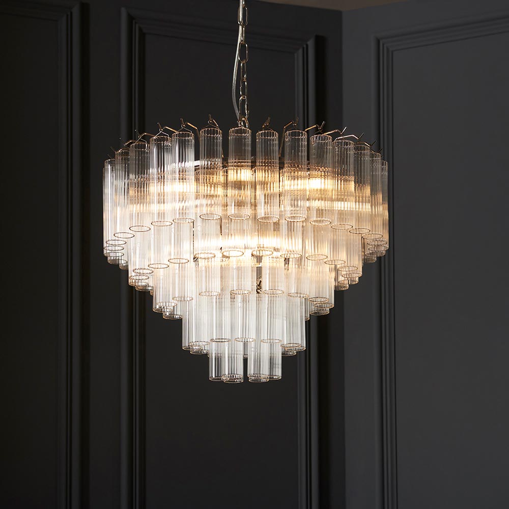 Endon Cranshaw 12 light tiered pendant with ribbed clear glass cylinders on polished chrome, suspended by chain against a dark panelled wall.