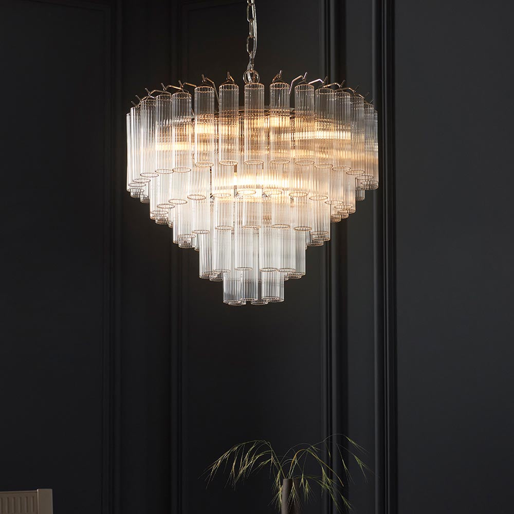 Endon Cranshaw 12 light tiered pendant with ribbed clear glass cylinders and polished chrome metalwork, suspended from a chain against a dark panelled wall.