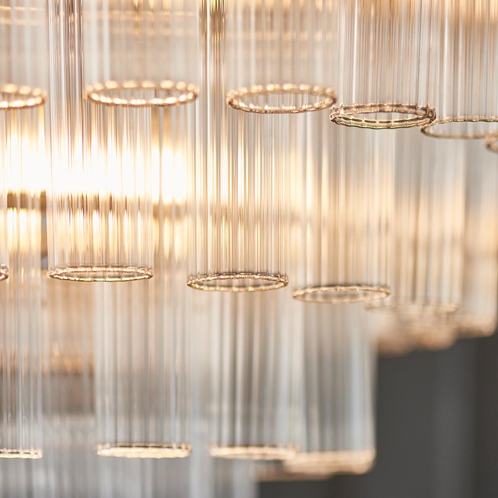 Close-up of Endon Cranshaw 12 Light Tiered Pendant in chrome, showing ribbed clear glass cylinders suspended from polished chrome rings with warm illumination.