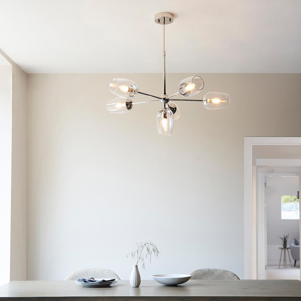 Endon Caldworth 6 Light Pendant in nickel with slender curved arms and clear blown glass shades, hanging above a dining table in a neutral room.