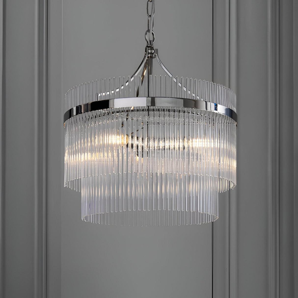 Beaumont 3 Light Pendant in nickel with tiered clear glass rods and chain suspension, hanging against a grey panelled wall.
