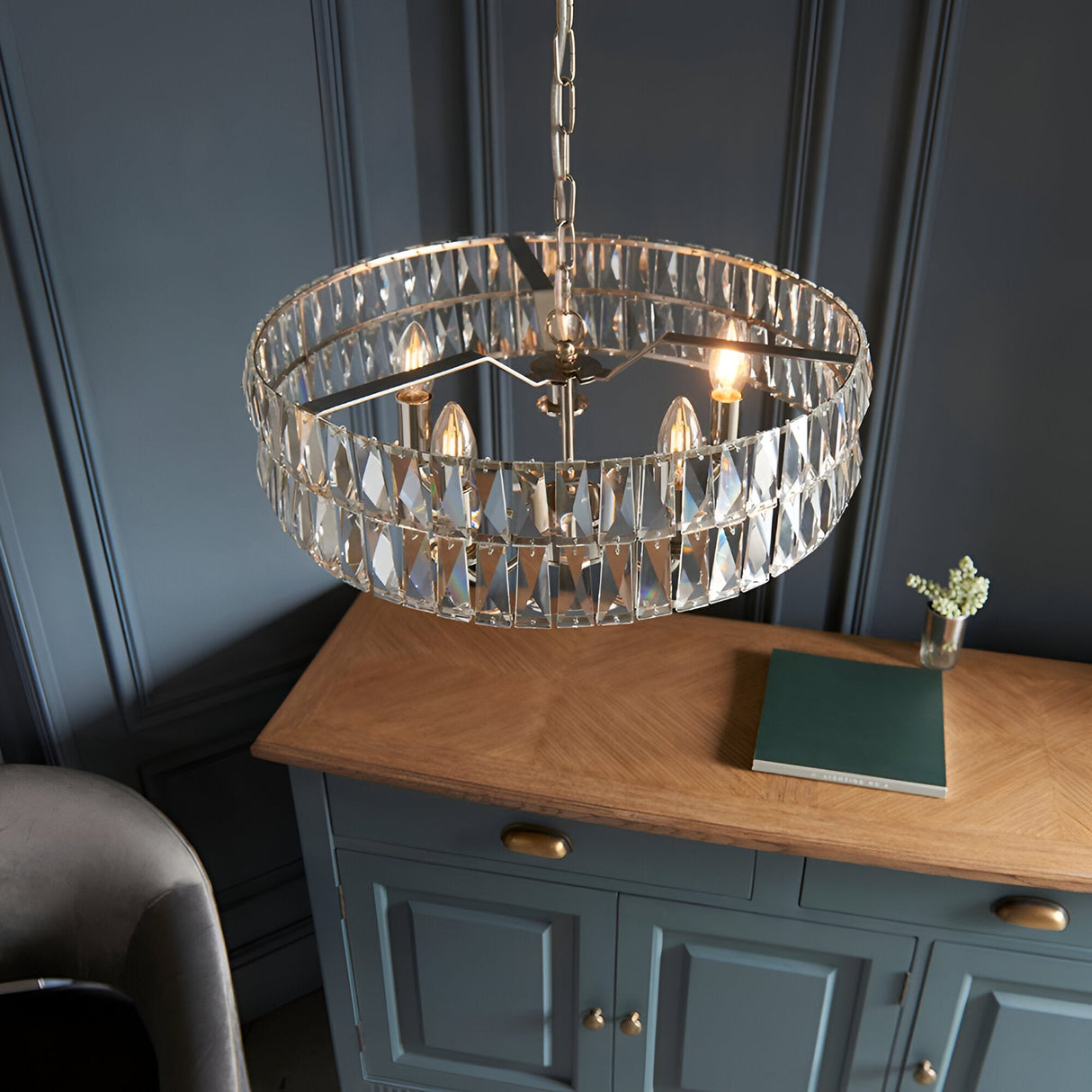 Endon Bevmont 5 light pendant in nickel with cut faceted glass drum shade on a chain, hung above an oak-topped blue sideboard in a panelled room.