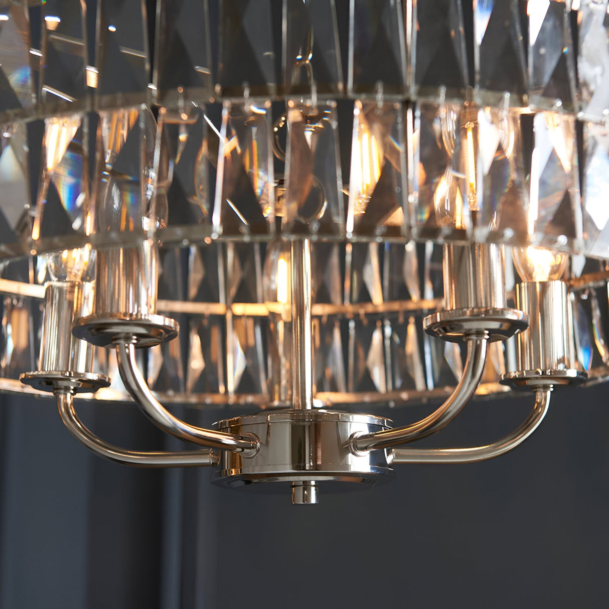 Close-up of Endon Bevmont 5 light pendant showing nickel arms, central column and tiered clear cut faceted glass shades with lit E14 bulbs.