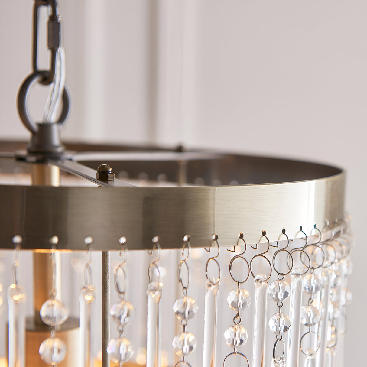 Close-up of the Bramgrove Pendant in antique brass, showing the drum frame with hooked fittings holding clear glass droplets and rods.