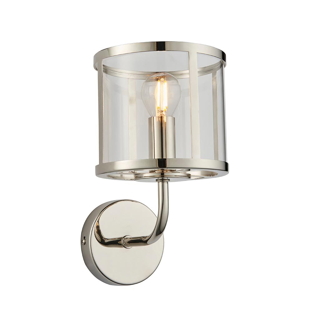 Ellery Wall Light in nickel with a cylindrical clear glass shade, single E14 bulb, curved arm and round backplate, on a plain white background.