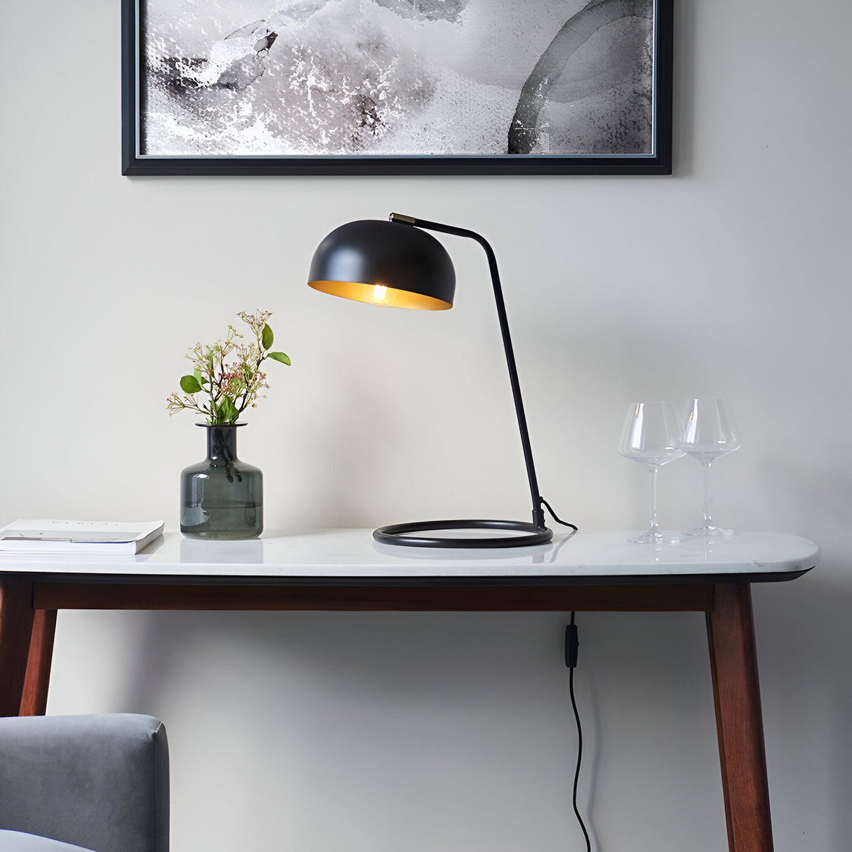 Ashdon Table Lamp in matt black with brass-toned inner shade, on a marble-top console table below framed wall art.