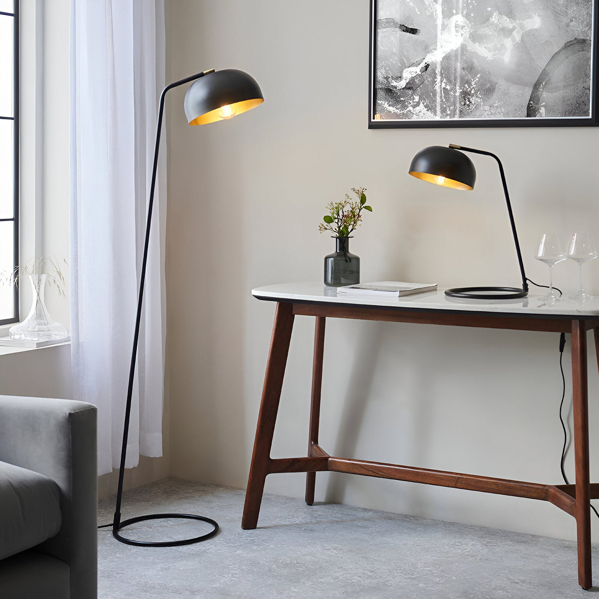 Endon Ashdon floor lamp in matt black with brass-lined dome shade beside a walnut console table with matching desk lamp in a living room.