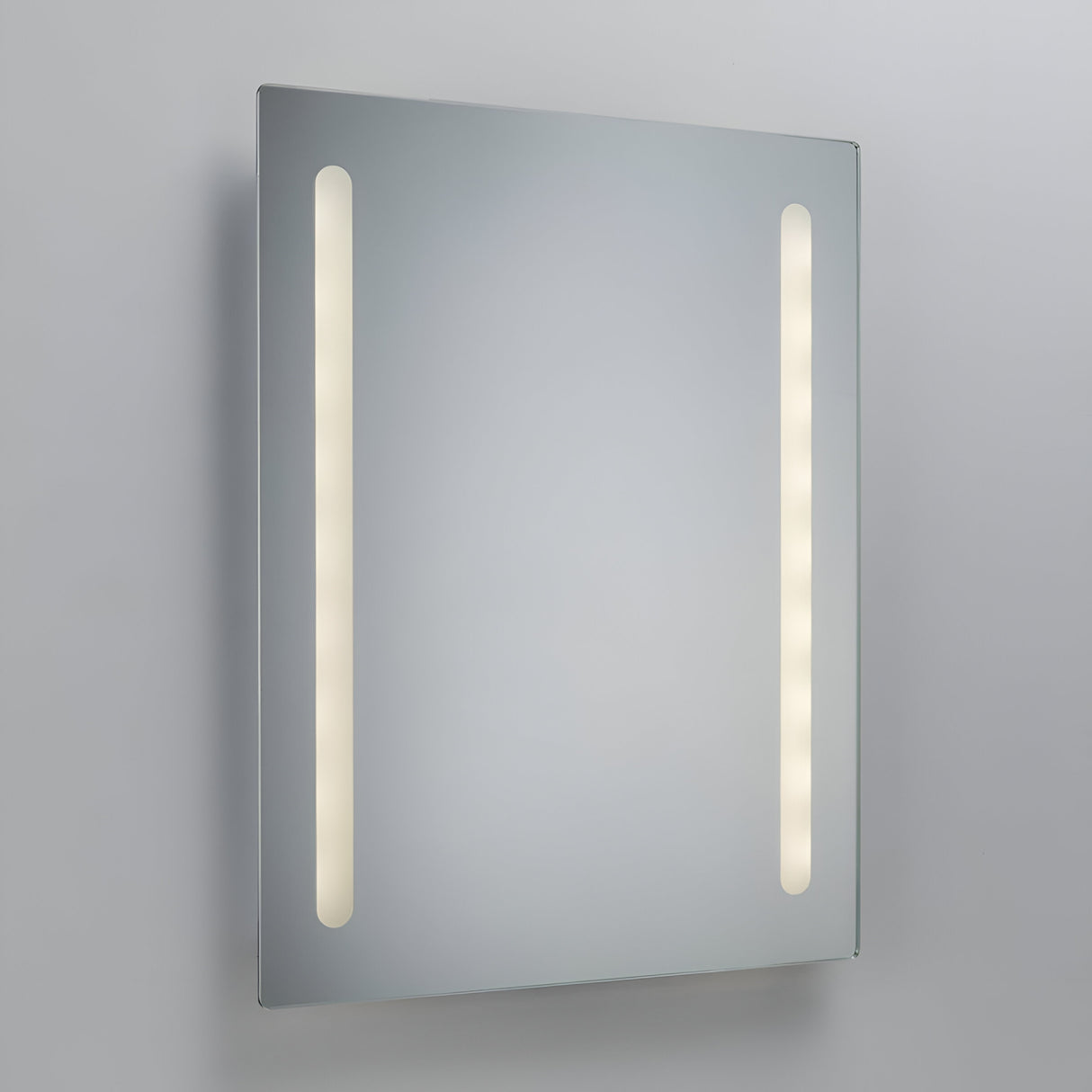 The 60x45cm LED Battery Bathroom Mirror features two vertical cool white LED light strips on either side, set against a plain gray background. The lights provide a soft, even ambient glow, enhancing the room's tranquility.