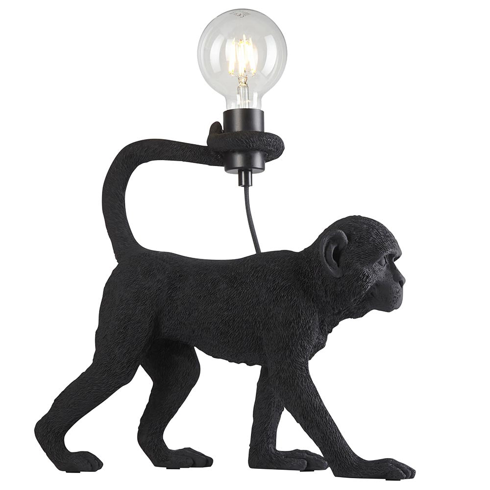 Belvoir Table Lamp in black, a resin monkey figure holding an exposed filament bulb aloft, shown on a plain white background.
