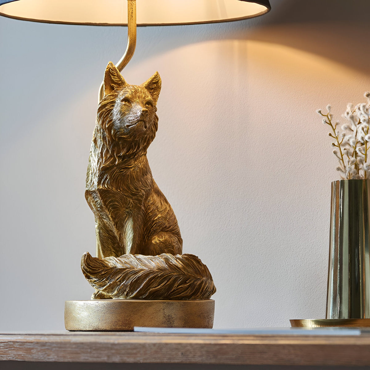 Endon Brambury table lamp with a vintage gold resin fox base and black tapered fabric shade, styled on a wooden console beside a brass vase.