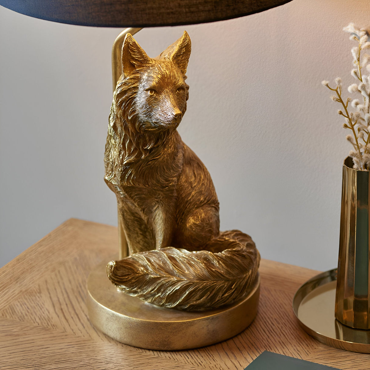 Endon Brambury table lamp with a hand-painted vintage gold resin fox base and black tapered fabric shade, on a wooden side table.
