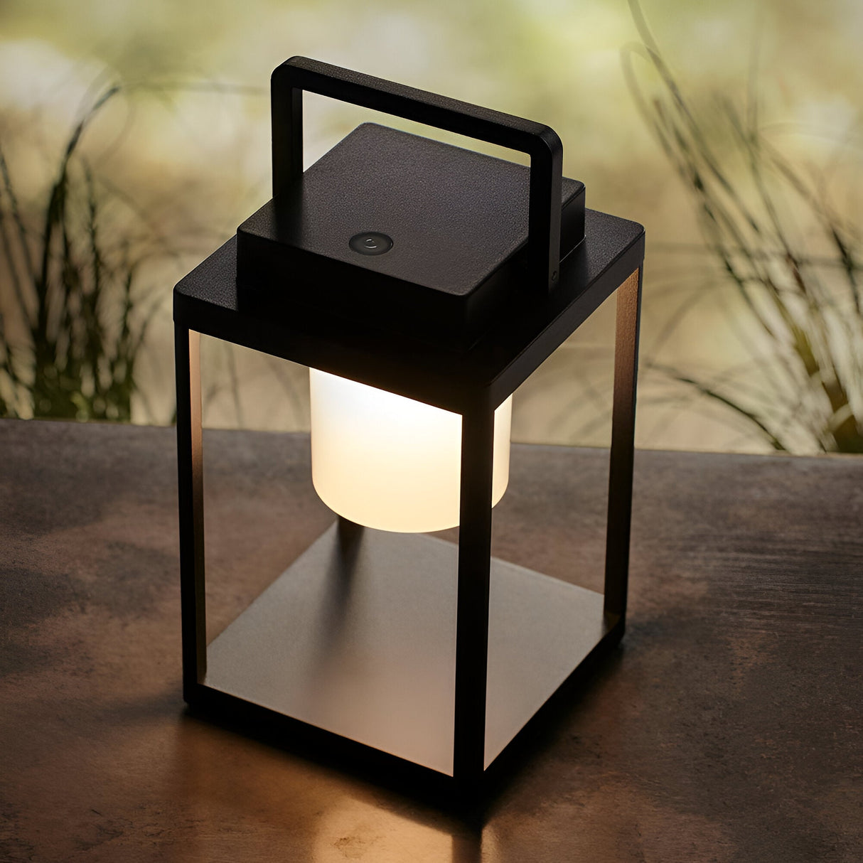 Endon Danedon portable LED table lamp in matt black aluminium with white polycarbonate diffuser and carry handle, lit on an outdoor table.