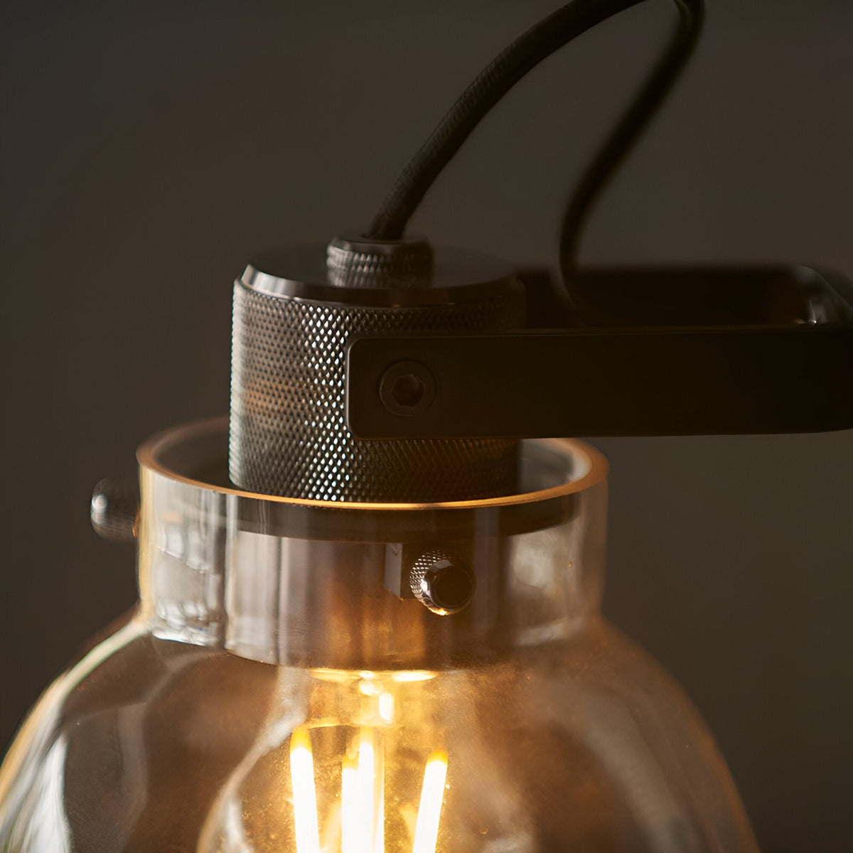 Close-up of Endon Camden task lamp with knurled black-chrome fittings, adjustable head bracket and smoked grey glass shade with lit E27 filament bulb.